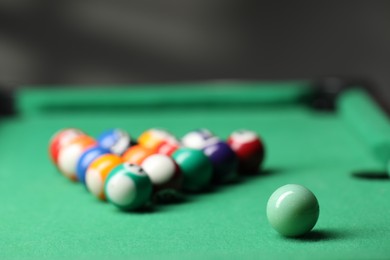 Photo of Billiard balls in triangle on green table indoors, closeup. Space for text