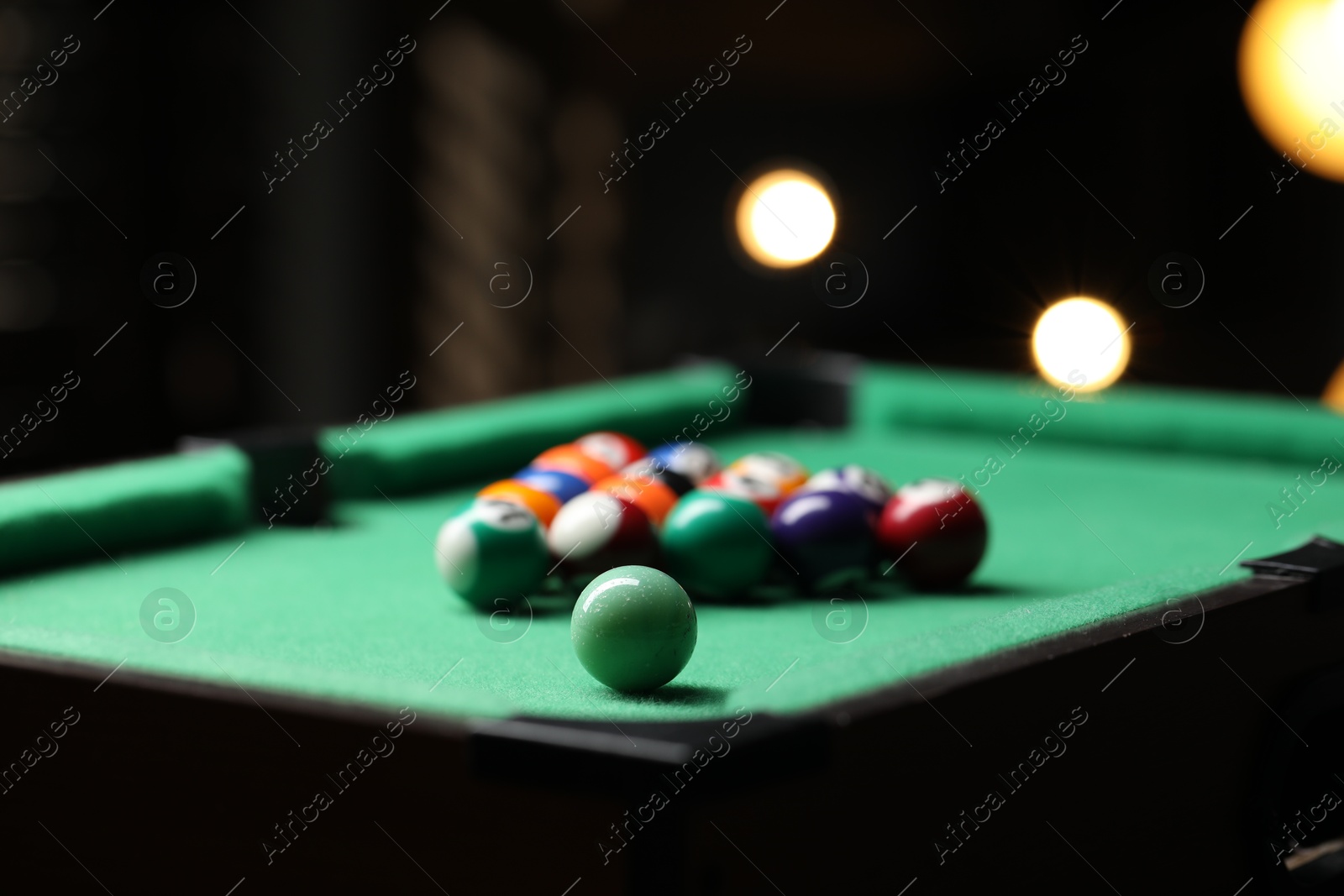 Photo of Billiard balls in triangle on green table indoors, closeup. Space for text