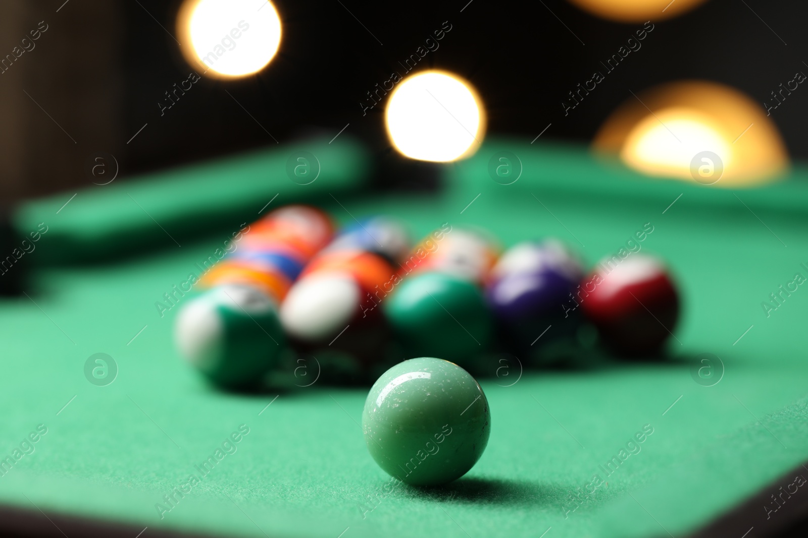 Photo of Billiard balls in triangle on green table indoors, closeup