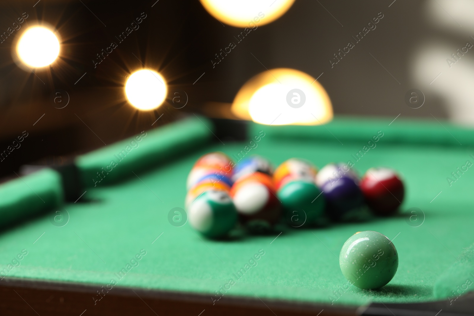 Photo of Billiard balls in triangle on green table indoors, closeup. Space for text