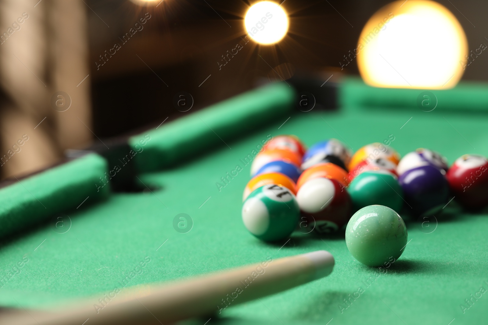 Photo of Billiard balls in triangle and cue on green table indoors, closeup. Space for text