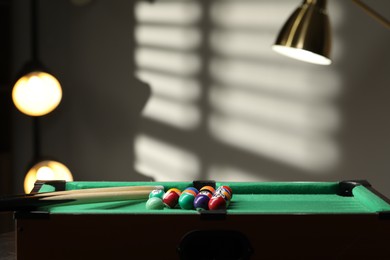 Photo of Billiard balls in triangle and cues on green table indoors. Space for text