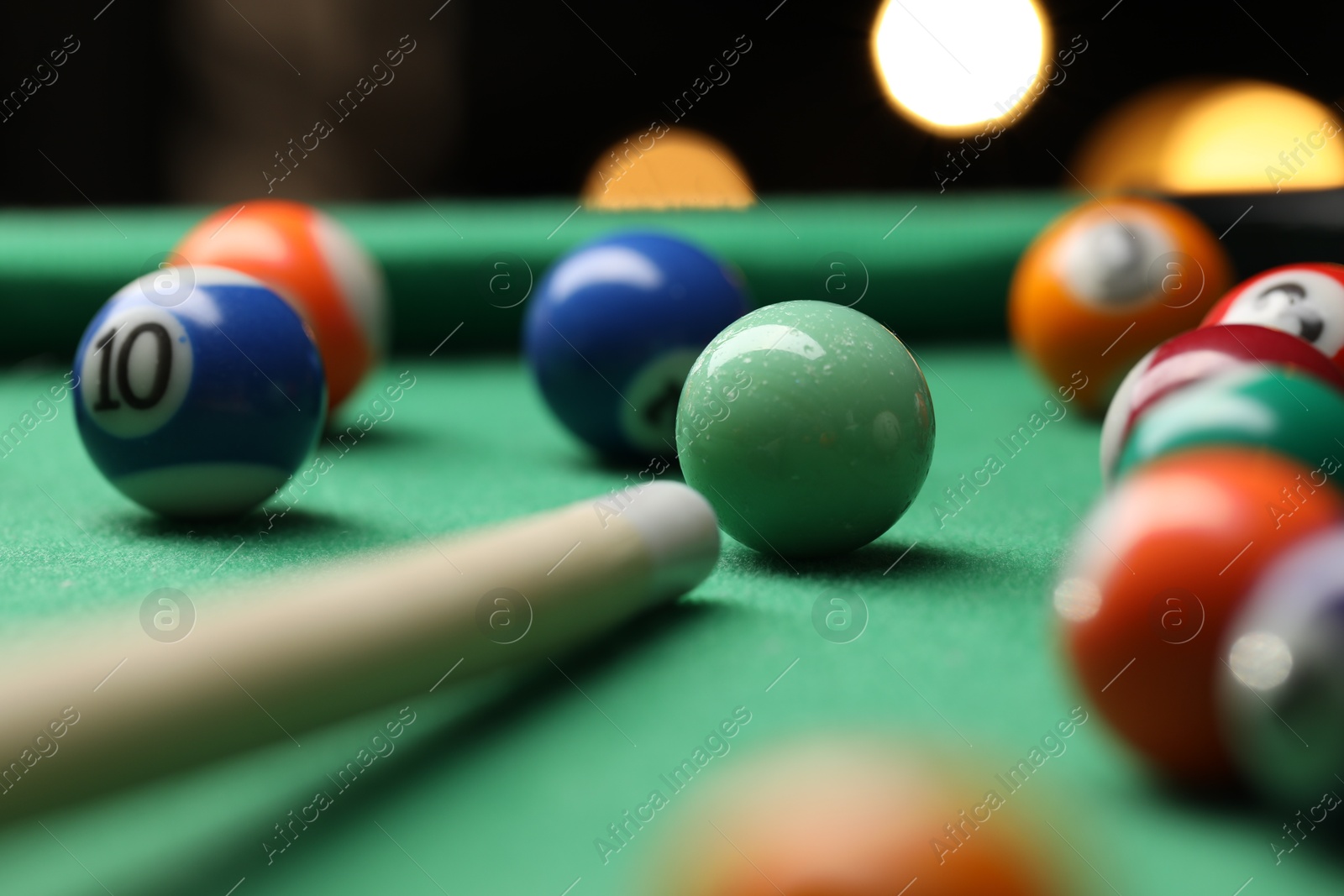 Photo of Many colorful billiard balls and cue on green table indoors, closeup