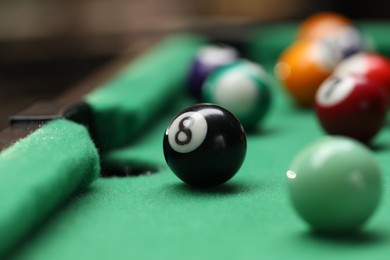 Photo of Many colorful billiard balls on green table indoors, closeup