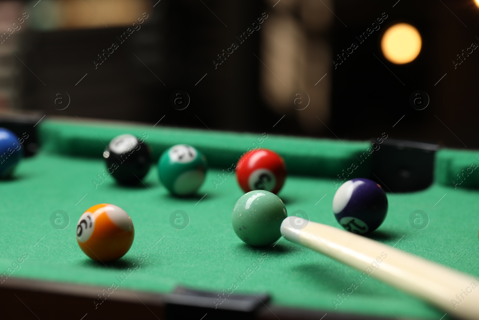 Photo of Many colorful billiard balls and cue on green table indoors, closeup. Space for text