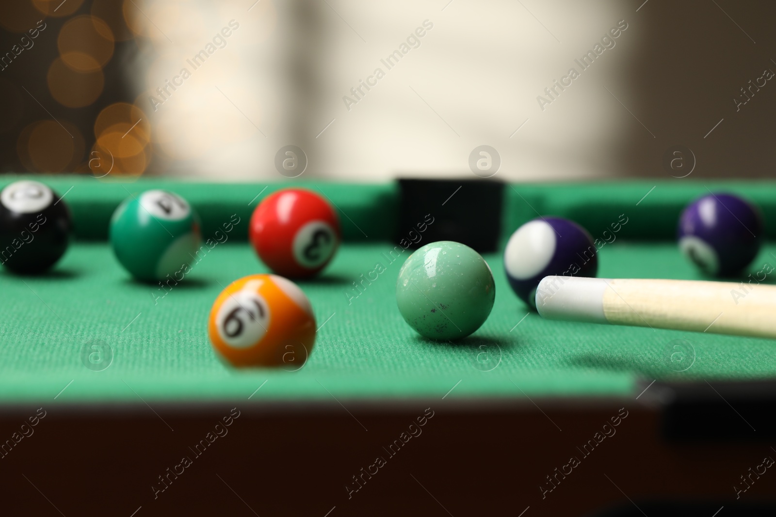 Photo of Many colorful billiard balls and cue on green table indoors, closeup. Space for text