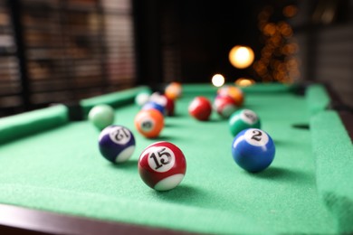 Photo of Many colorful billiard balls on green table indoors, closeup