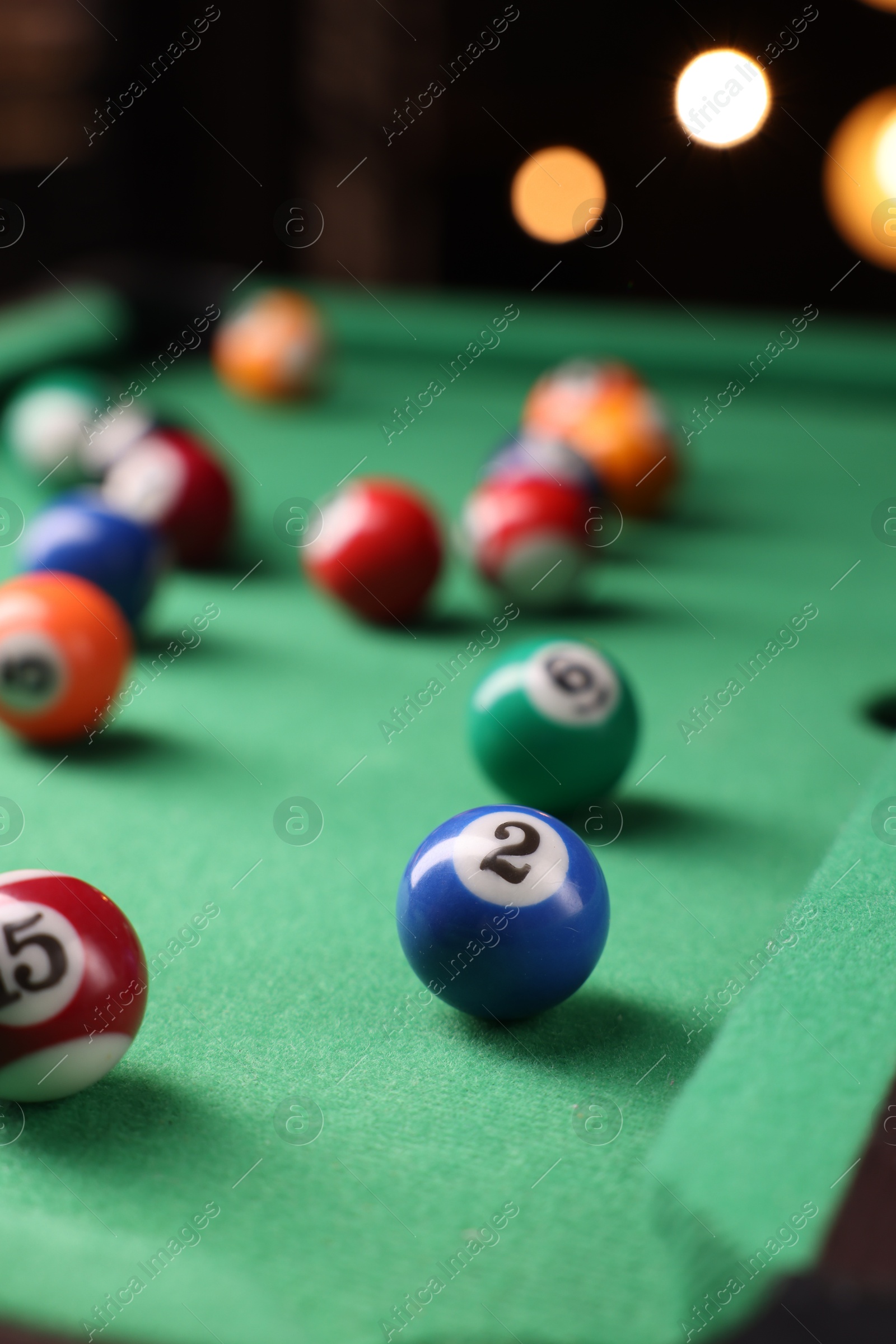 Photo of Many colorful billiard balls on green table indoors, closeup