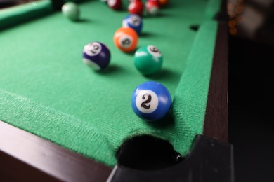 Photo of Many colorful billiard balls on green table indoors, closeup