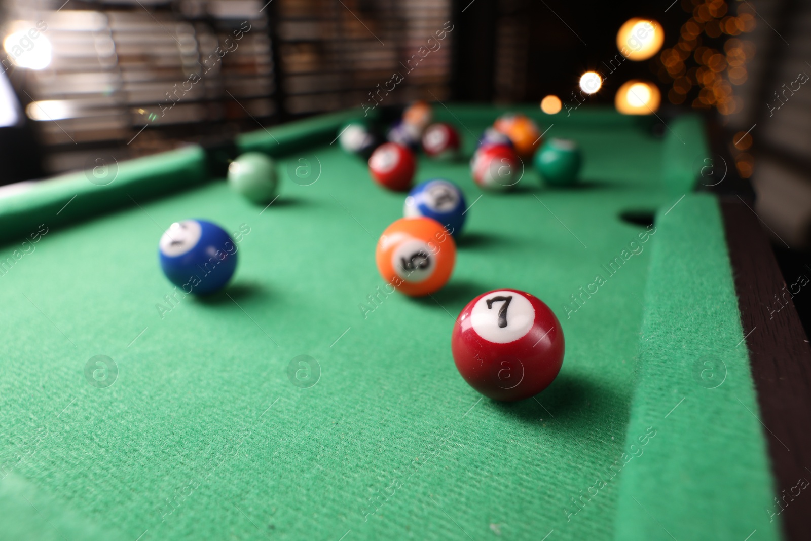 Photo of Many colorful billiard balls on green table indoors, closeup