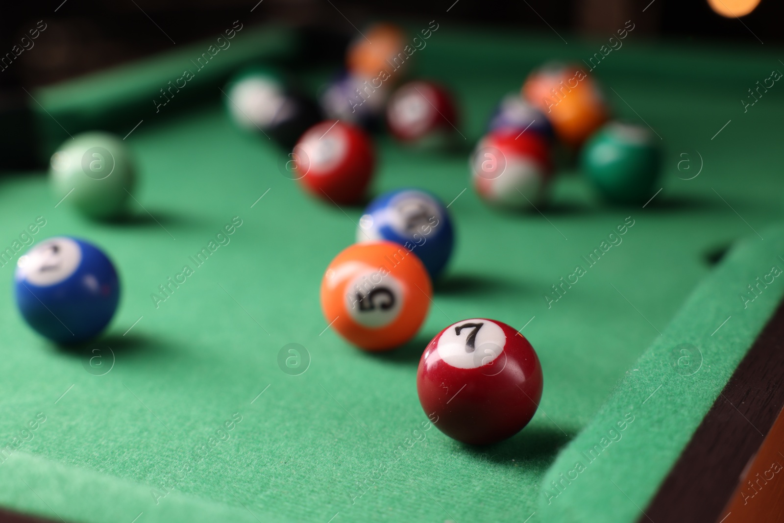 Photo of Many colorful billiard balls on green table indoors, closeup