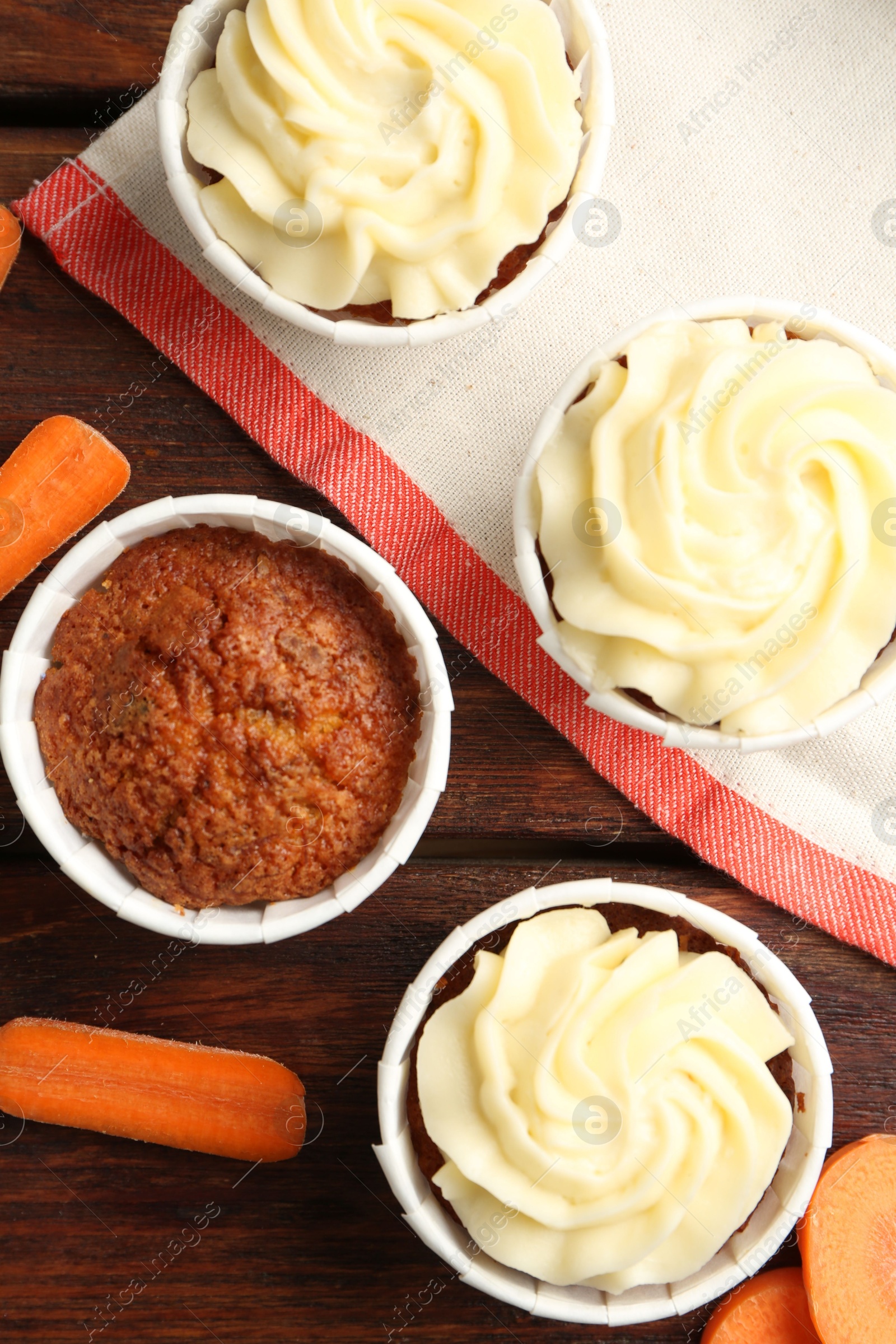 Photo of Delicious carrot muffins and fresh vegetables on wooden table, flat lay