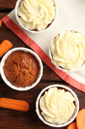 Photo of Delicious carrot muffins and fresh vegetables on wooden table, flat lay