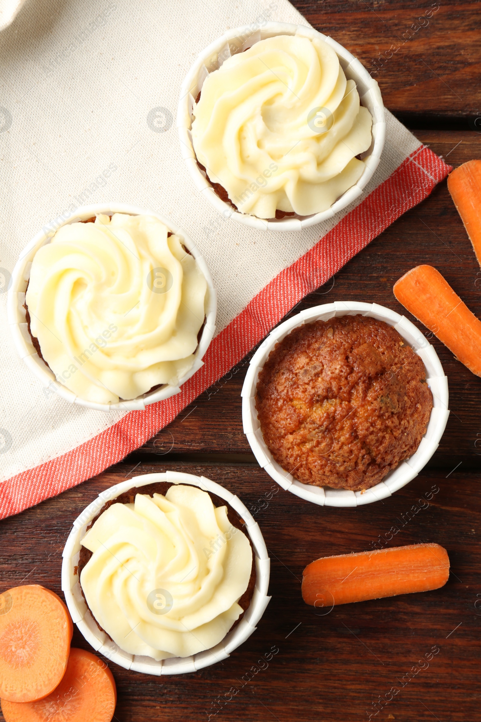 Photo of Delicious carrot muffins and fresh vegetables on wooden table, flat lay