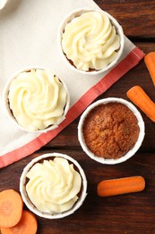 Photo of Delicious carrot muffins and fresh vegetables on wooden table, flat lay