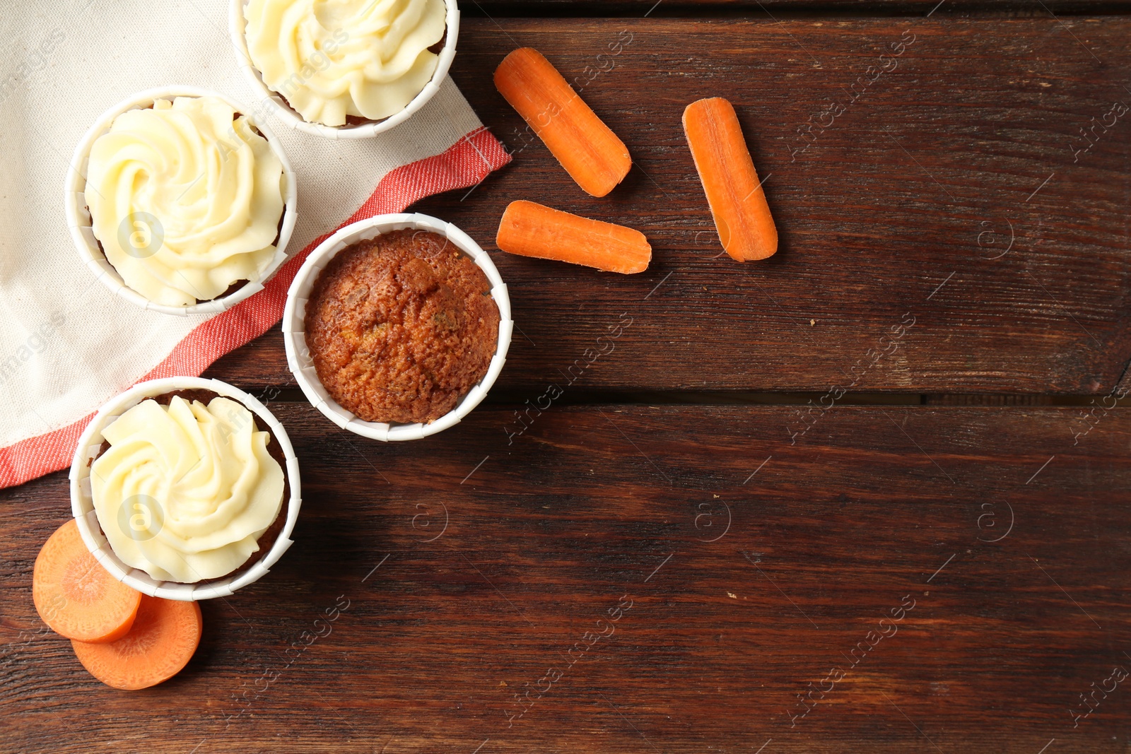 Photo of Delicious carrot muffins and fresh vegetables on wooden table, flat lay. Space for text