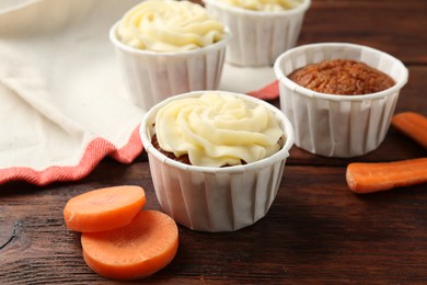 Photo of Delicious carrot muffins and fresh vegetables on wooden table, closeup