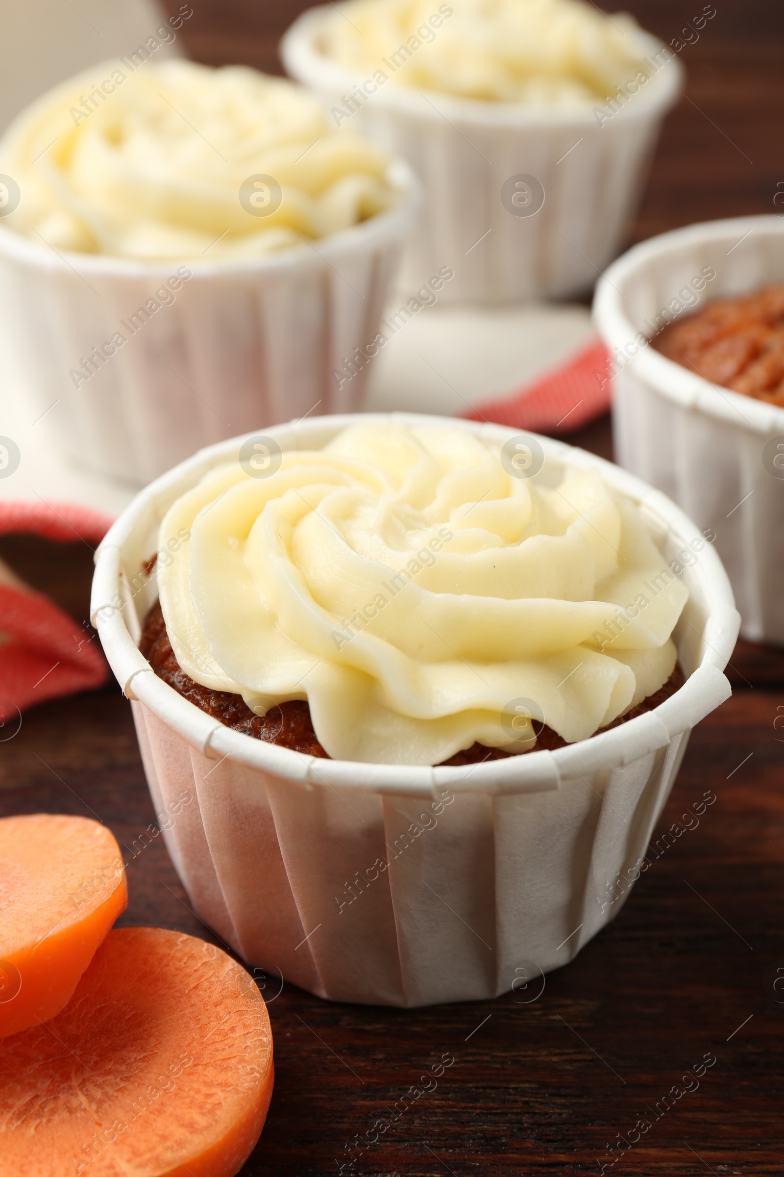 Photo of Delicious carrot muffins and fresh vegetable on wooden table, closeup