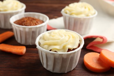 Photo of Delicious carrot muffins and fresh vegetable on wooden table, closeup