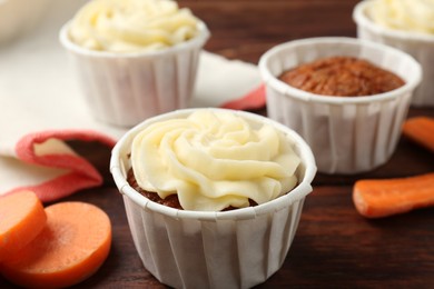 Photo of Delicious carrot muffins and fresh vegetable on wooden table, closeup