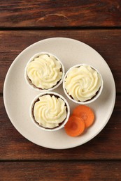 Photo of Delicious carrot muffins and fresh vegetable on wooden table, top view