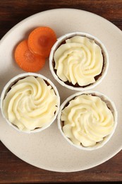 Photo of Delicious carrot muffins and fresh vegetable on wooden table, top view