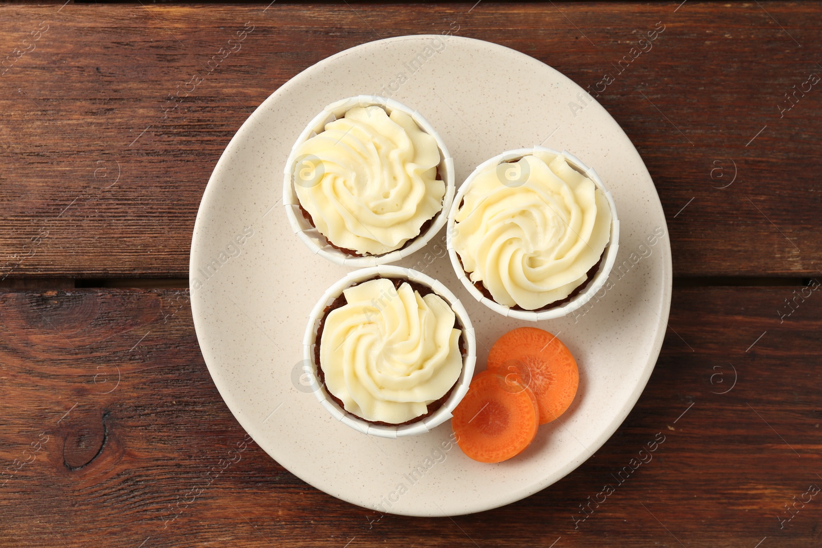 Photo of Delicious carrot muffins and fresh vegetable on wooden table, top view