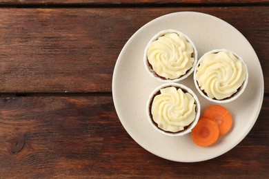 Photo of Delicious carrot muffins and fresh vegetable on wooden table, top view. Space for text