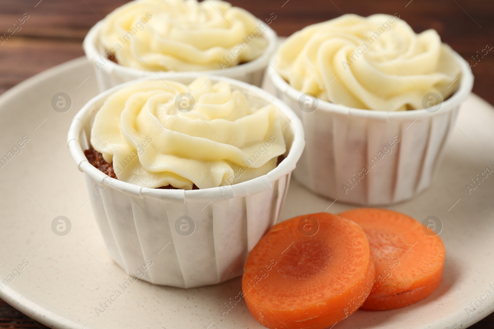 Photo of Delicious carrot muffins and fresh vegetable on table, closeup