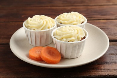 Photo of Delicious carrot muffins and fresh vegetable on wooden table, closeup