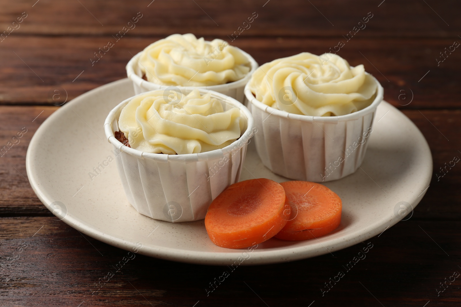 Photo of Delicious carrot muffins and fresh vegetable on wooden table, closeup