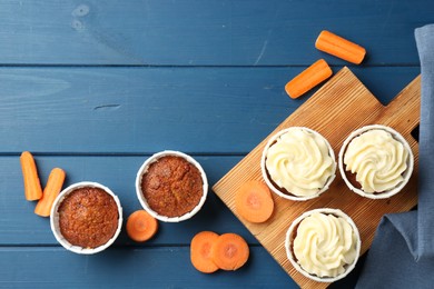 Photo of Delicious carrot muffins and fresh vegetables on blue wooden table, flat lay. Space for text