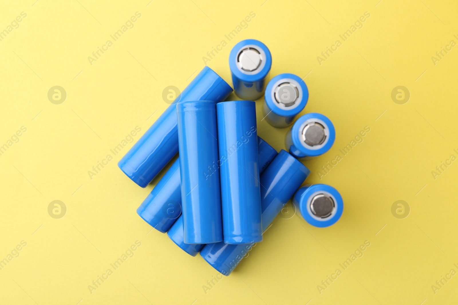 Photo of Many AA cell batteries on yellow background, top view