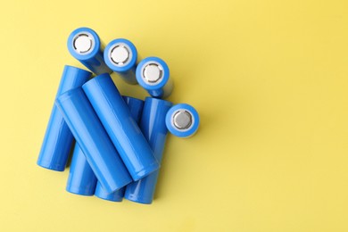 Photo of Many AA cell batteries on yellow background, top view. Space for text