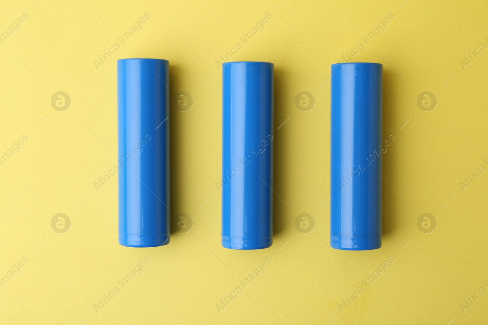 Photo of Three AA cell batteries on yellow background, top view