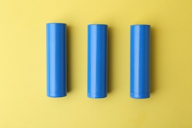 Photo of Three AA cell batteries on yellow background, top view