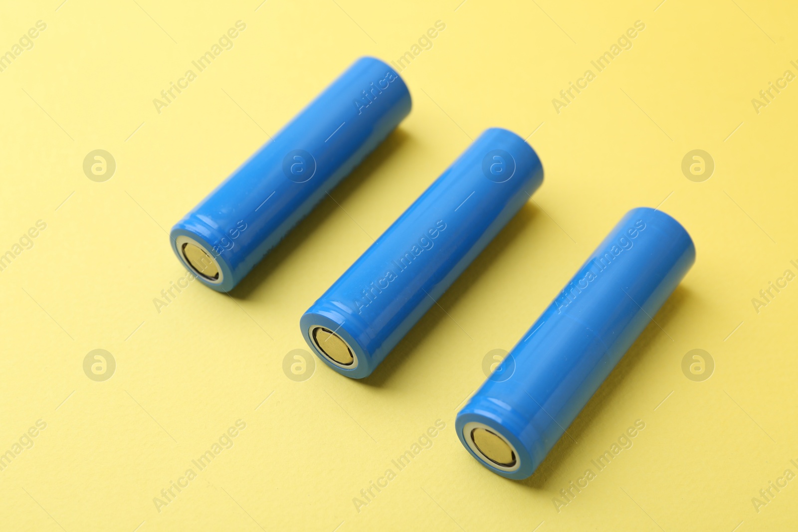 Photo of Three AA cell batteries on yellow background, closeup