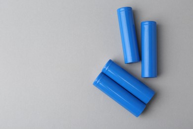 Photo of Many AA cell batteries on light grey background, top view. Space for text