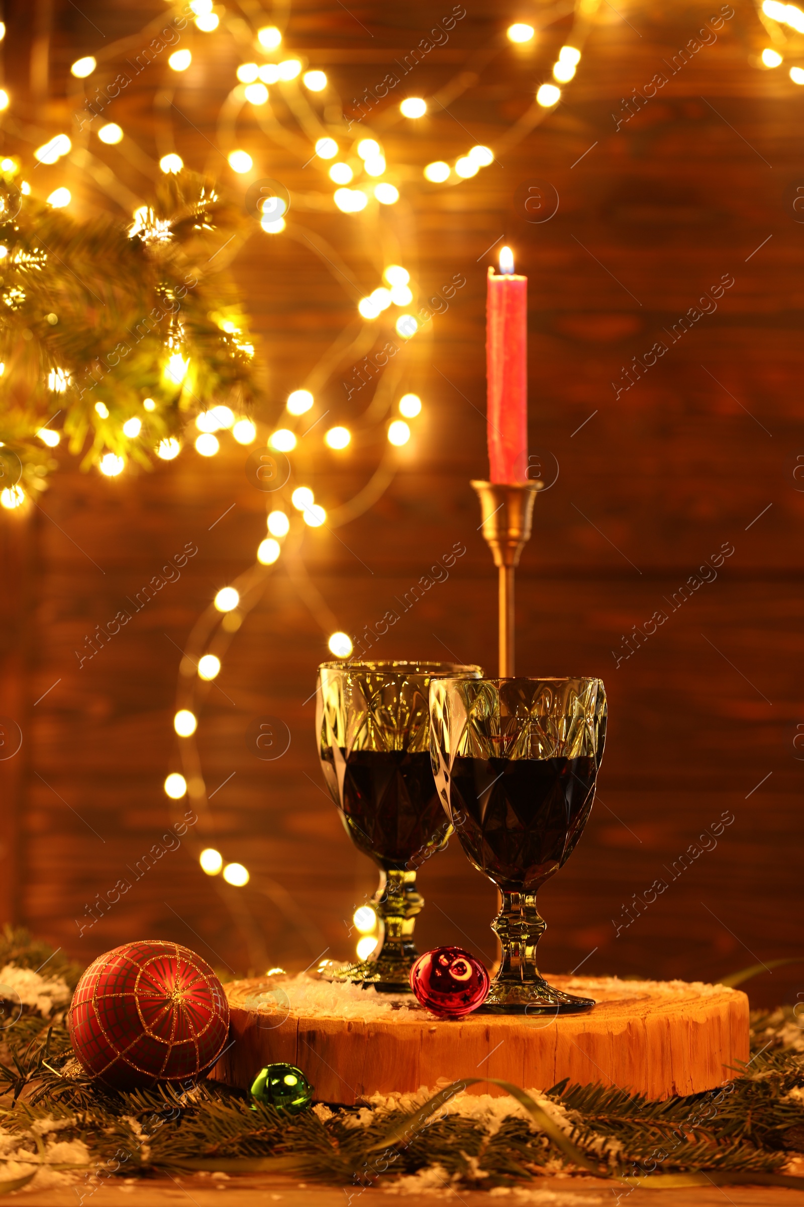 Photo of Red wine and beautiful Christmas decor on wooden table against blurred festive lights