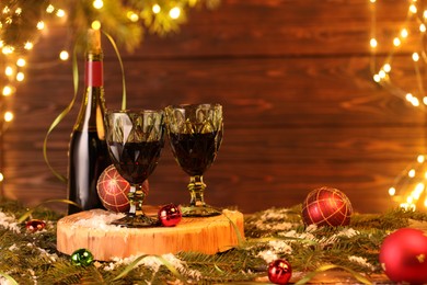 Photo of Red wine and beautiful Christmas decor on wooden table against blurred festive lights. Space for text