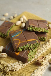 Photo of Pieces of Dubai chocolate bar with pistachios and knafeh on light table, closeup