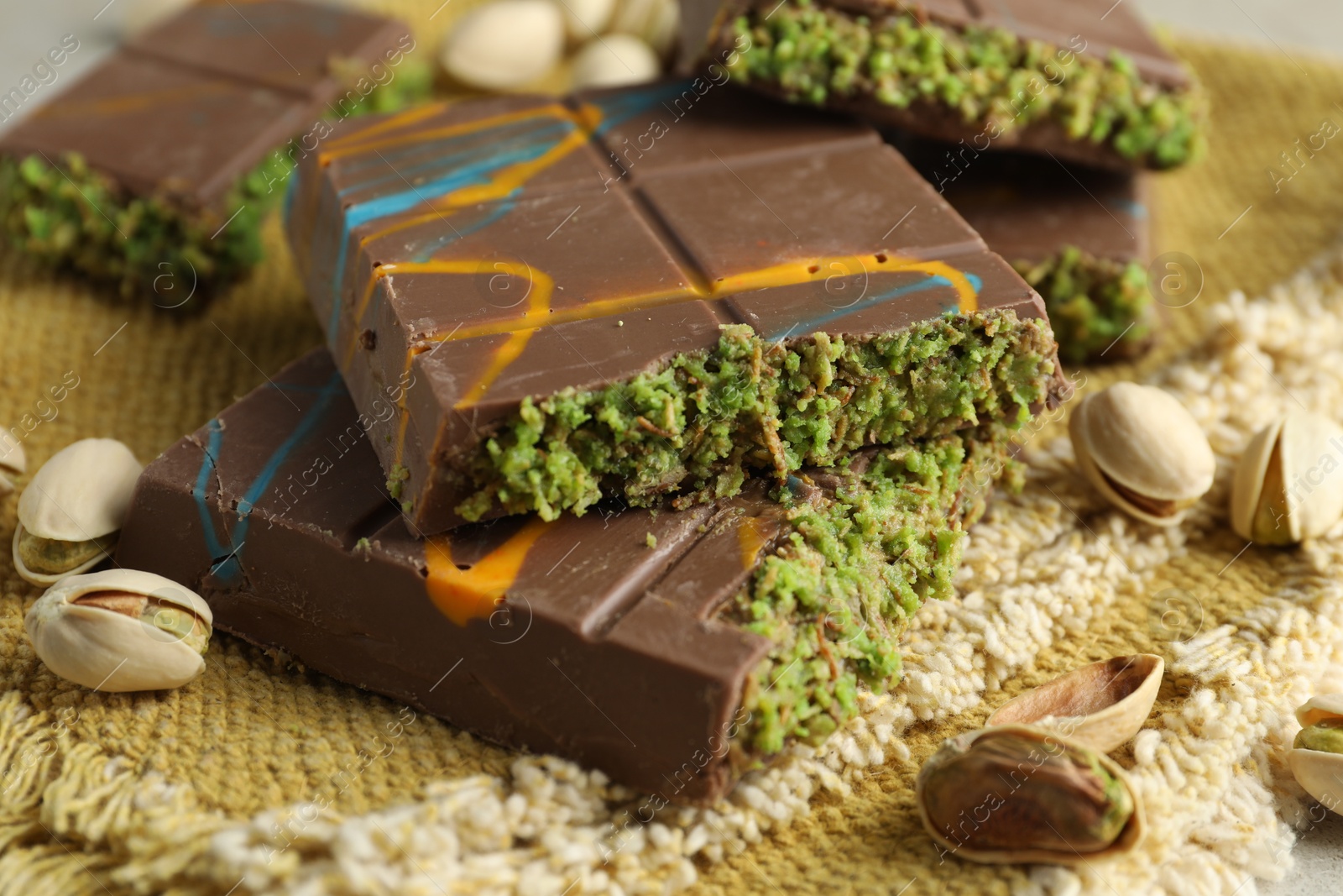 Photo of Pieces of Dubai chocolate bar with pistachios and knafeh on table, closeup