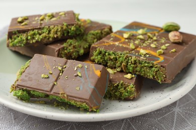 Photo of Pieces of Dubai chocolate bars with pistachio and knafeh on white table, closeup