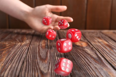 Image of Woman throwing red dice on wooden table, closeup