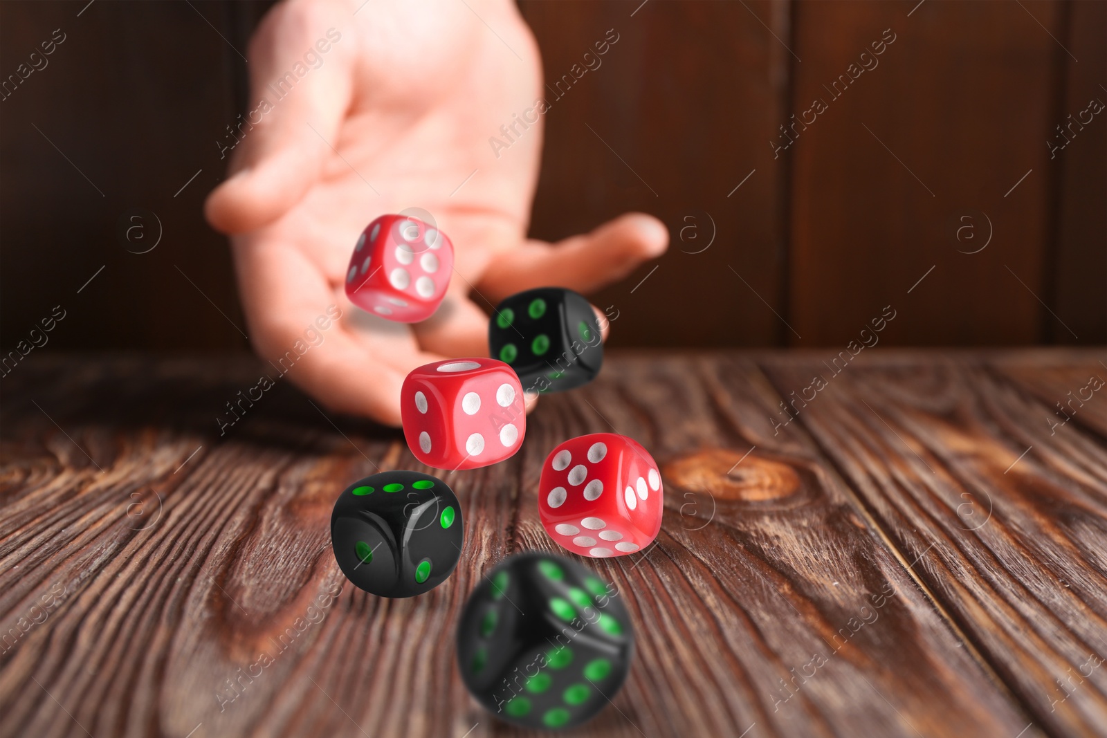 Image of Man throwing dice on wooden table, closeup. Space for text