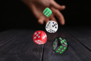 Image of Man throwing dice on black wooden table, closeup