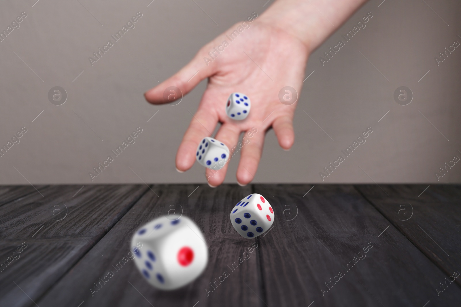 Image of Woman throwing white dice on black wooden table, closeup