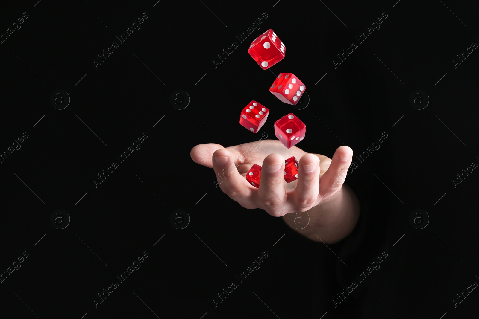 Image of Man throwing red dice in darkness, closeup. Space for text