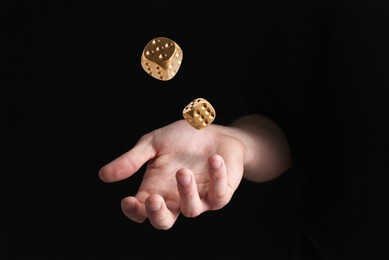 Image of Man throwing gold dice in darkness, closeup