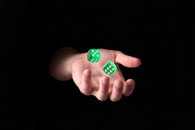 Image of Man throwing green dice in darkness, closeup